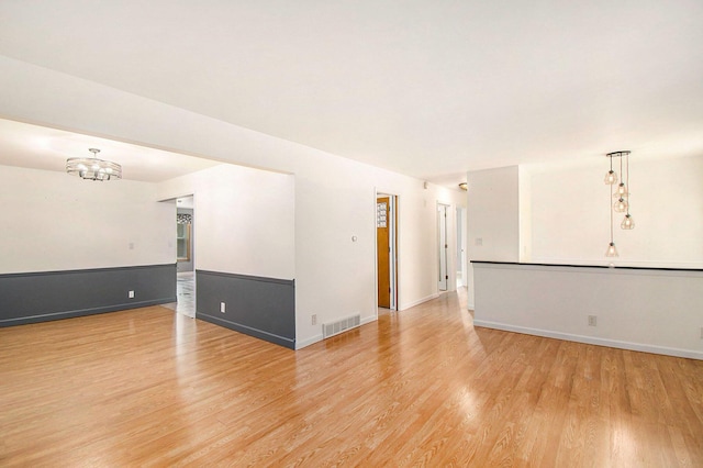 4741 Pin Oak Trl, Jackson, MI 49201 - empty room with visible vents, light wood finished floors, baseboards, and an inviting chandelier