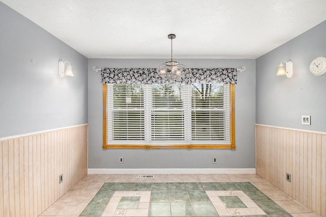 4741 Pin Oak Trl, Jackson, MI 49201 - unfurnished dining area with tile patterned flooring, a chandelier, wood walls, a wainscoted wall, and visible vents