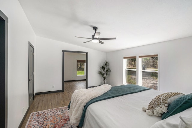 bedroom with baseboards, ceiling fan, wood finished floors, and lofted ceiling