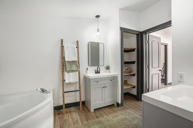 full bath featuring vanity, a bath, and wood finished floors