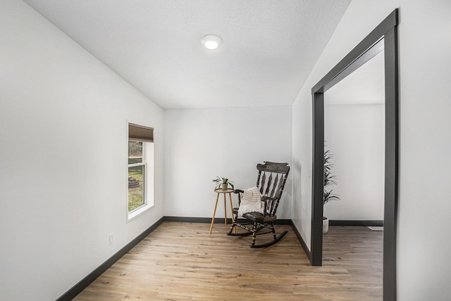 sitting room with baseboards and light wood-type flooring