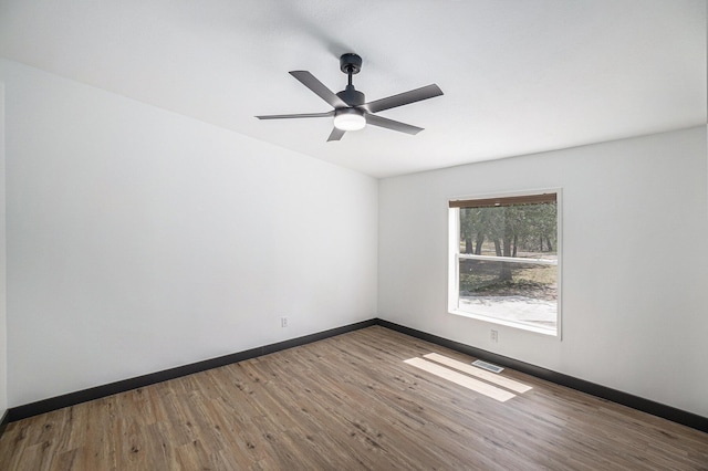 empty room featuring ceiling fan, baseboards, visible vents, and wood finished floors
