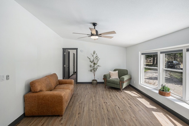 living area with a ceiling fan, baseboards, and wood finished floors