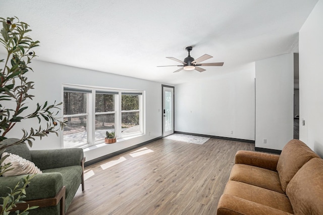living area with baseboards, a ceiling fan, and wood finished floors