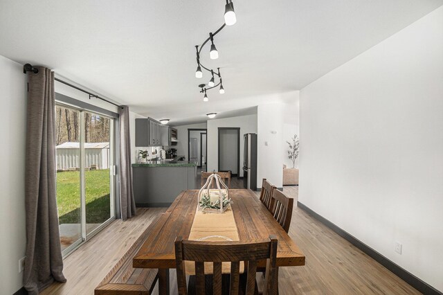 1499 N Apple Dr, White Cloud, MI 49349 - dining space with rail lighting, baseboards, lofted ceiling, and light wood-style floors