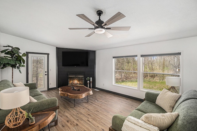 1499 N Apple Dr, White Cloud, MI 49349 - living room featuring ceiling fan, a fireplace, vaulted ceiling, wood finished floors, and baseboards