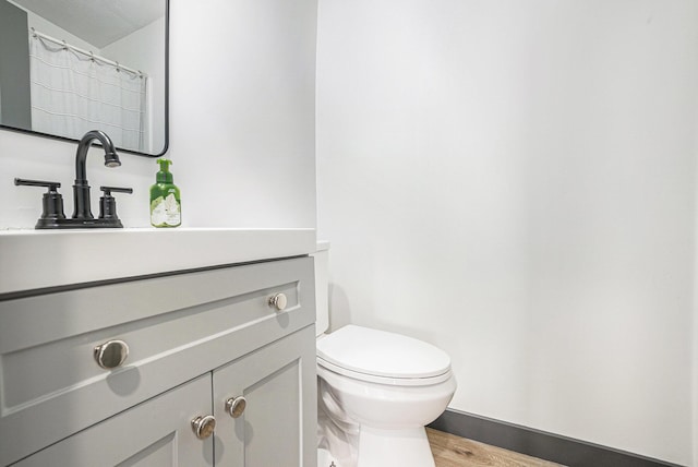 full bath with vanity, baseboards, toilet, and wood finished floors