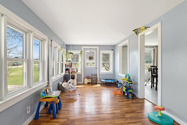 sunroom featuring baseboards, plenty of natural light, and wood finished floors