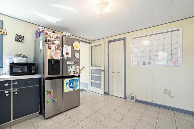 kitchen featuring visible vents, light tile patterned flooring, black microwave, light countertops, and stainless steel fridge with ice dispenser