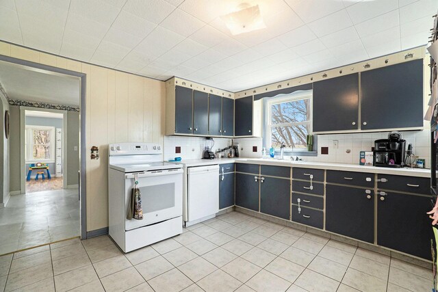 kitchen with light countertops, light tile patterned floors, backsplash, and white appliances
