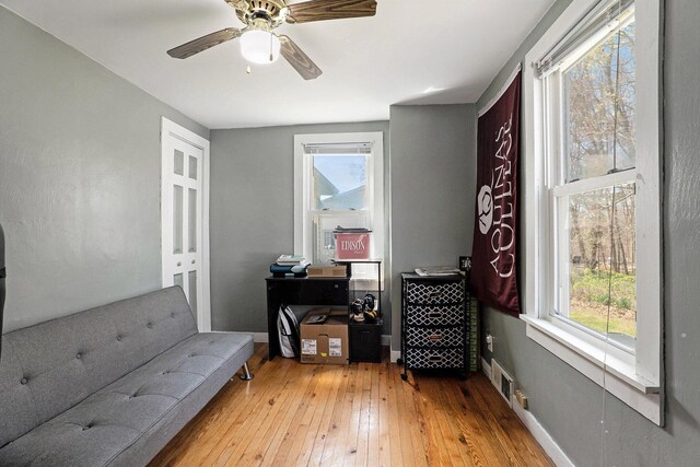 living area with wood-type flooring, ceiling fan, and baseboards