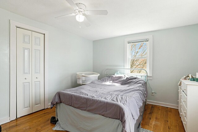 bedroom featuring baseboards, a ceiling fan, wood finished floors, and a closet