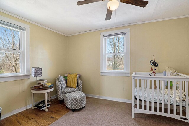 bedroom featuring crown molding, a nursery area, baseboards, and a ceiling fan