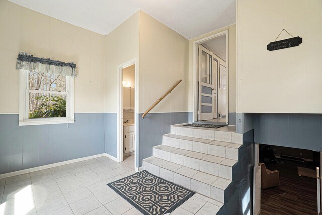 stairway with tile patterned flooring, baseboards, and a wainscoted wall