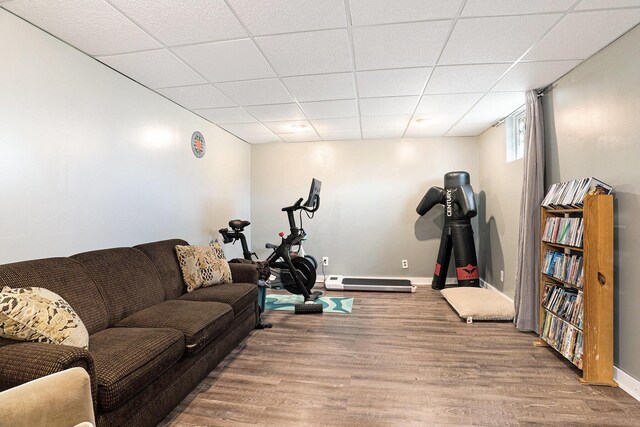 living area featuring baseboards, a drop ceiling, and wood finished floors