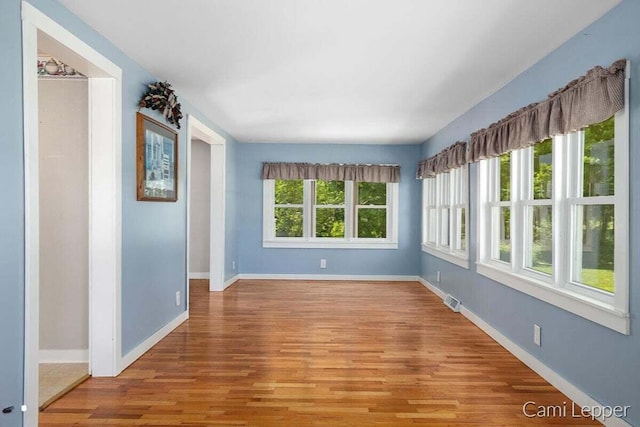 empty room with visible vents, baseboards, and wood finished floors