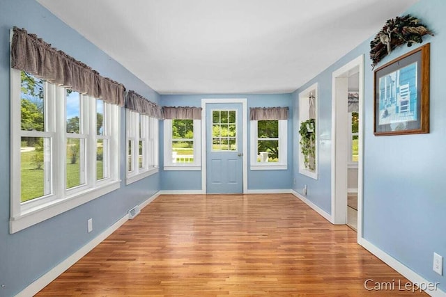 unfurnished sunroom with baseboards and wood finished floors