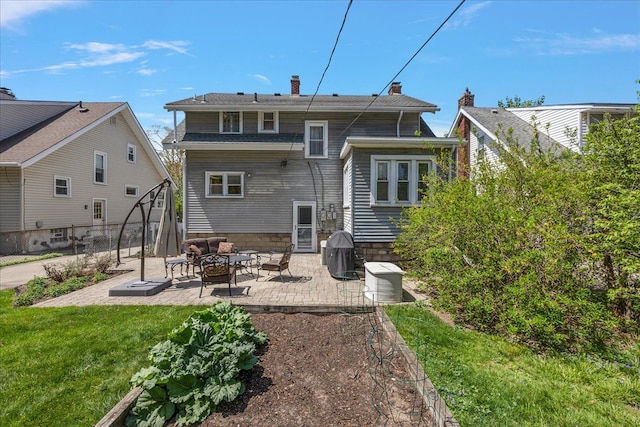 rear view of house featuring fence, a patio, a chimney, a lawn, and an outdoor fire pit
