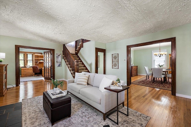 living area featuring an inviting chandelier, plenty of natural light, stairway, and hardwood / wood-style floors