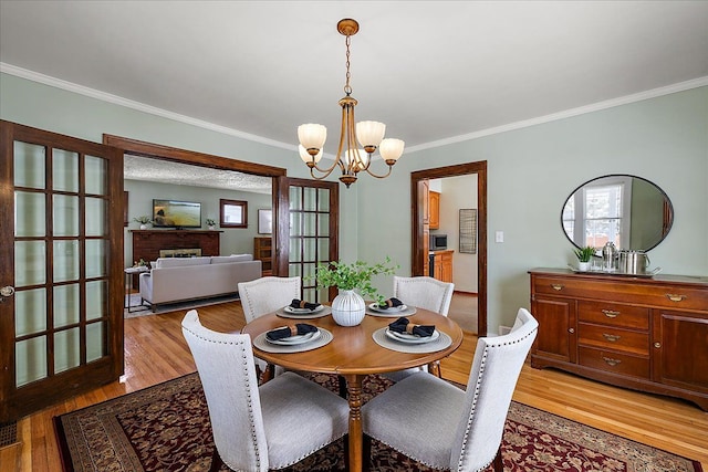 dining space featuring ornamental molding, light wood-type flooring, and a chandelier