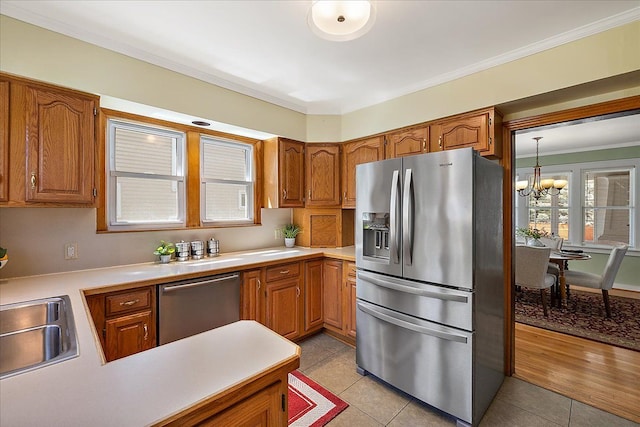 kitchen with brown cabinetry, appliances with stainless steel finishes, light tile patterned floors, light countertops, and a chandelier