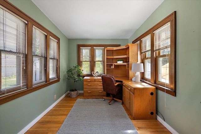 office space featuring built in study area, baseboards, and light wood-type flooring