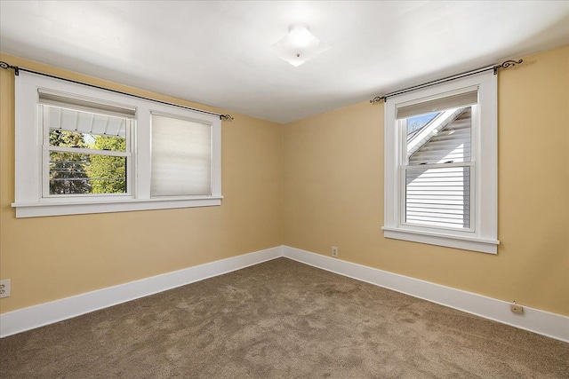 unfurnished room featuring dark colored carpet and baseboards