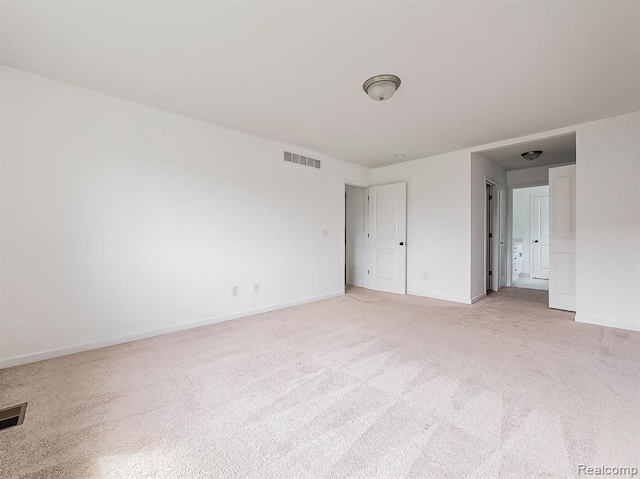 unfurnished bedroom with baseboards, light colored carpet, and visible vents