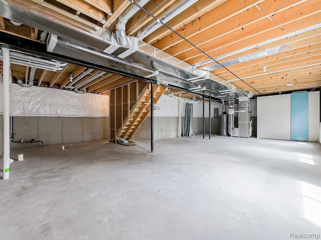 unfinished below grade area with heating unit, water heater, and stairway