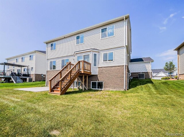back of house featuring stairs, a lawn, brick siding, and a deck