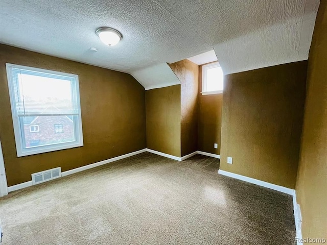 bonus room with a textured ceiling, vaulted ceiling, carpet flooring, and baseboards