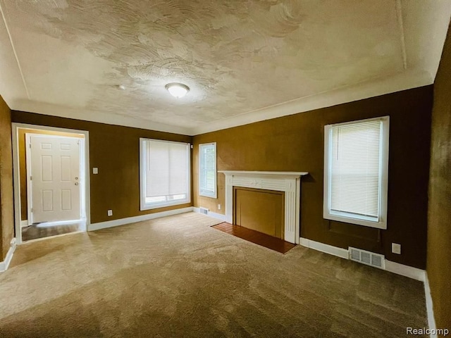 unfurnished living room featuring baseboards, carpet floors, a textured ceiling, and a fireplace