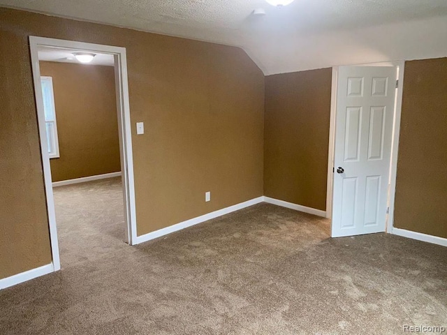 additional living space featuring carpet, lofted ceiling, and baseboards