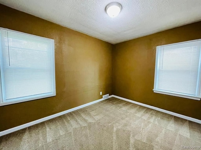 carpeted spare room with a textured ceiling and baseboards