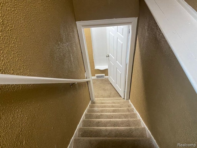 stairway featuring a textured wall and baseboards