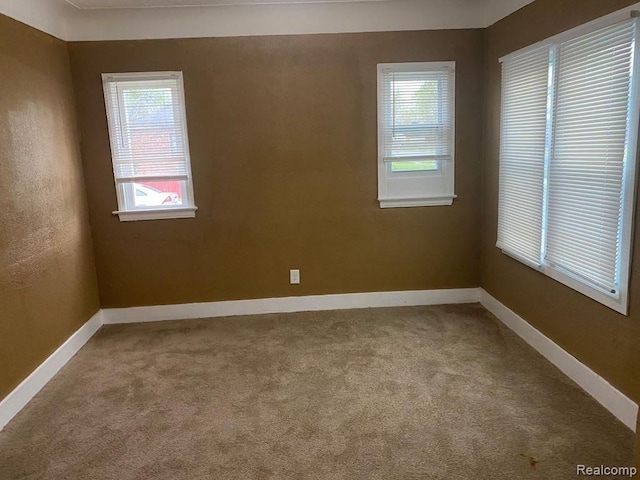 spare room featuring carpet and baseboards