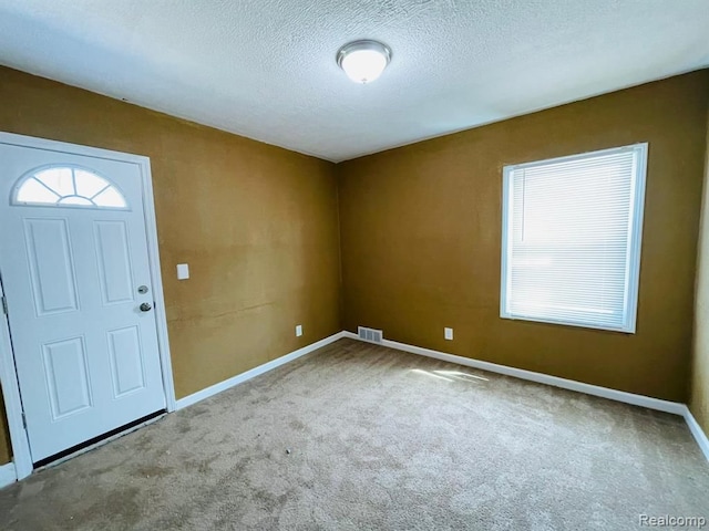 carpeted entryway featuring baseboards and a textured ceiling