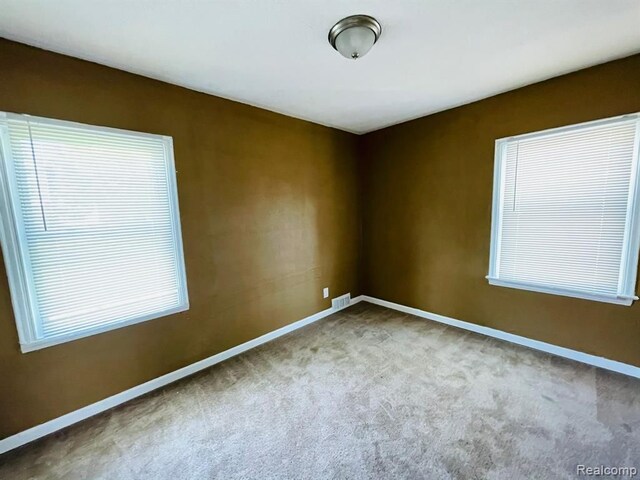 carpeted spare room featuring baseboards