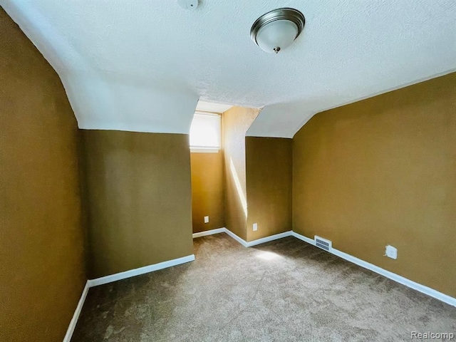 additional living space with carpet flooring, vaulted ceiling, a textured ceiling, and baseboards