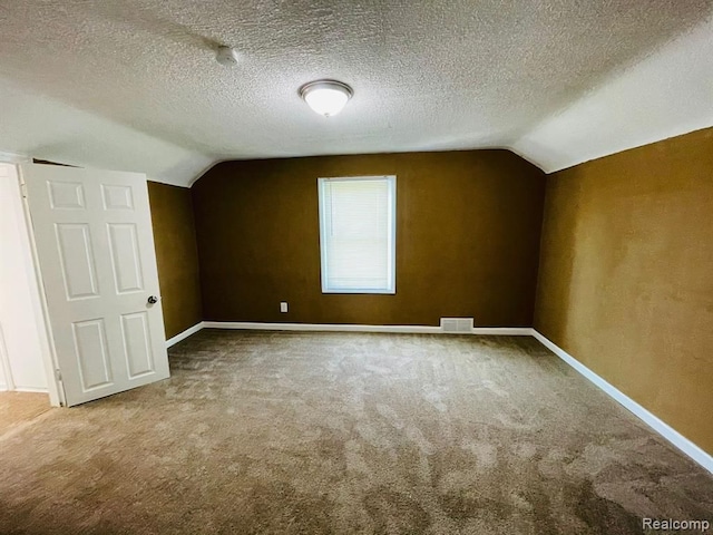 bonus room featuring lofted ceiling, carpet, baseboards, and a textured ceiling