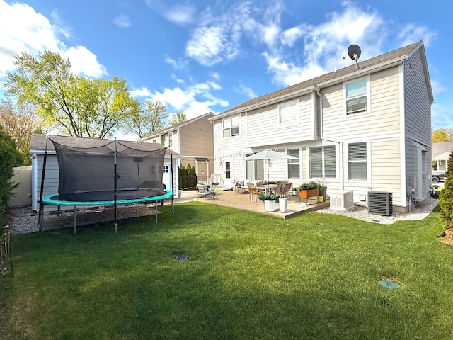 rear view of property with central air condition unit, a trampoline, a yard, and a patio