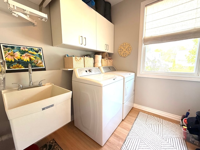 washroom with washing machine and dryer, light wood finished floors, cabinet space, and a wealth of natural light