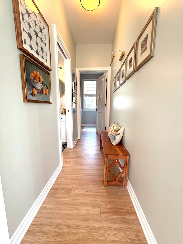 corridor with baseboards and light wood-style floors