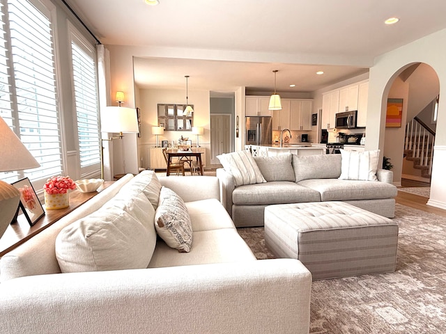 living room featuring recessed lighting, arched walkways, and stairway