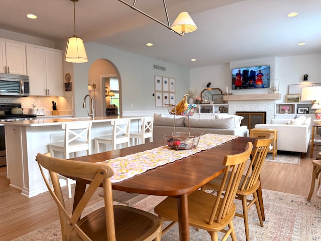 dining area with light wood-style floors, arched walkways, visible vents, and recessed lighting
