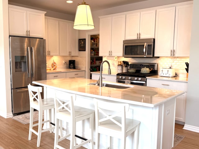 kitchen featuring decorative backsplash, light wood-type flooring, a sink, light countertops, and stainless steel appliances