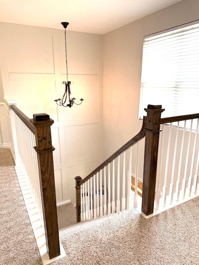 staircase with carpet floors and a notable chandelier