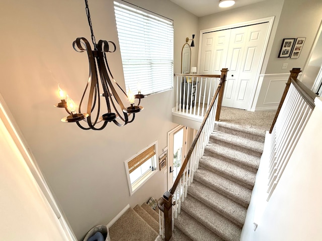 stairs with a chandelier, carpet, and a towering ceiling