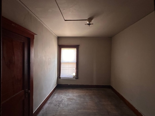 empty room with baseboards, dark wood-style floors, and attic access