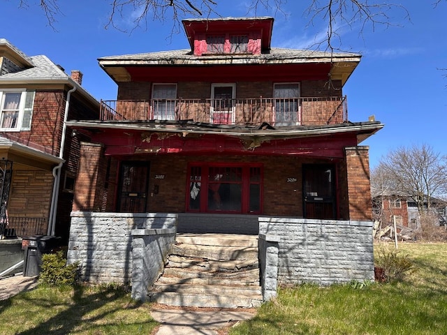 american foursquare style home with a porch, brick siding, and a balcony